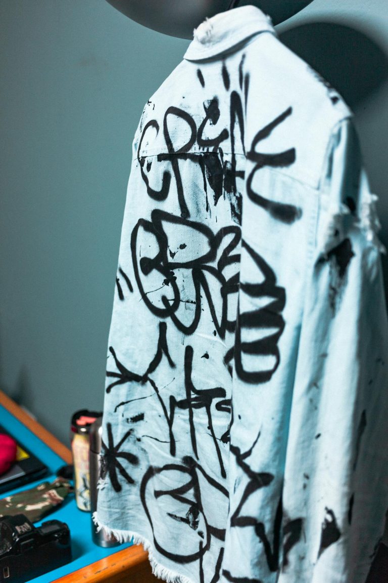 Denim shirt with graffiti art hanging indoors, showcasing streetwear and creativity.